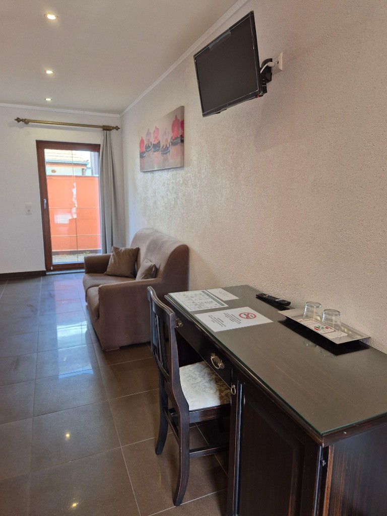 Aufgeräumter Hotelschreibtisch mit Gläsern, Fernseher und Sitzecke nach der Reinigung